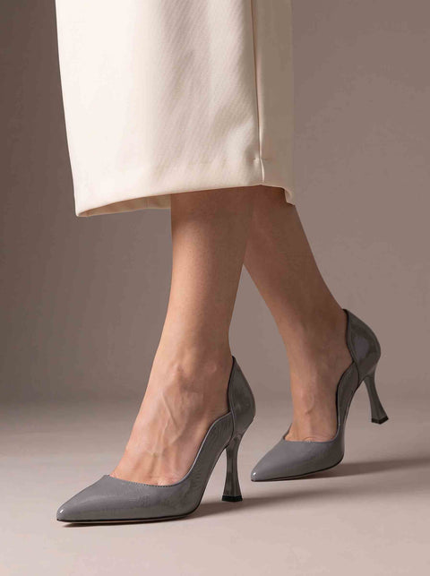 Gri sivri burun stiletto yürüyüş pozunda yandan; parlak rugan yüzey ve dalgalı yan kesim hattı