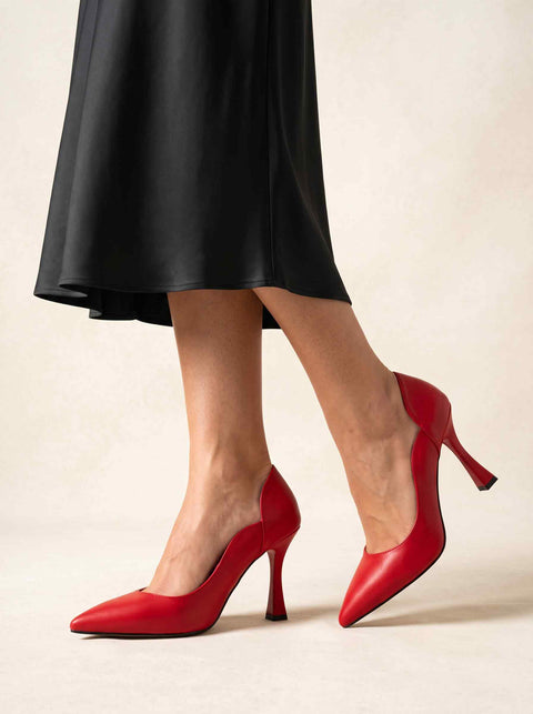 Kırmızı kavisli yan dekolteli sivri burun stiletto, model üzerinde yandan görünüm ve kadeh topuk detayı